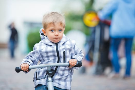 cute little boy rides his bike outdoors in city street