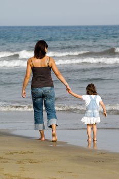 Mother and her child is walking at the beach.