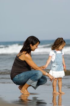 Mother and daughter together at the beach. The mother is expecting an other child.