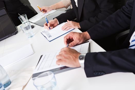 Team of business people taking notes at the meeting