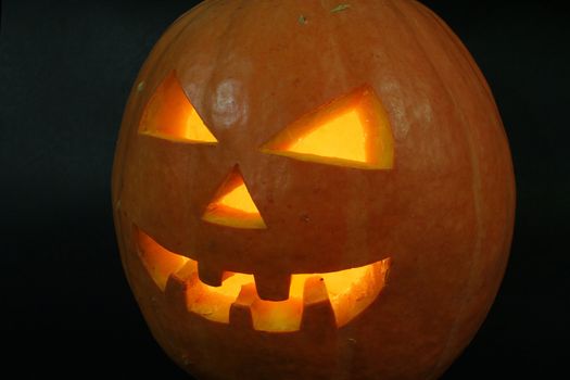 face of halloween pumpkin on black background with candle inside