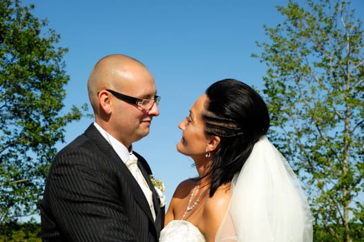 Bride and groom are standing close together looking at each other.