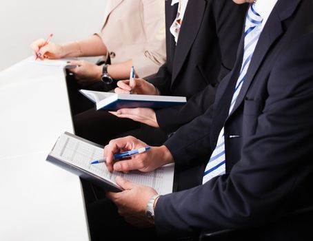 Team of business people taking notes at the meeting