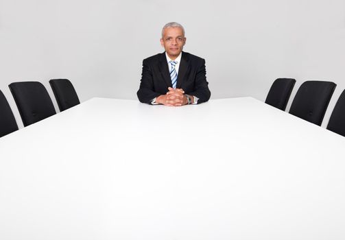 Businessman sitting alone in the empty boardroom