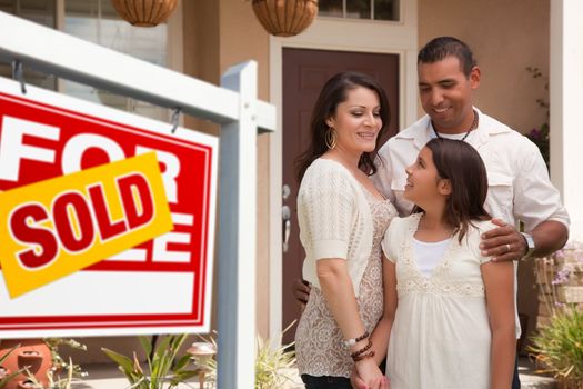 Hispanic Mother, Father and Daughter in Front of Their New Home with Sold Home For Sale Real Estate Sign.