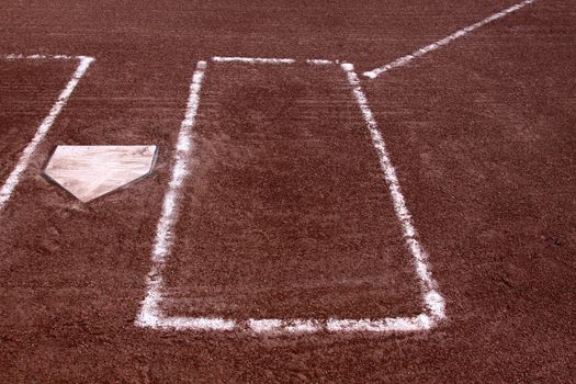 A close-up of the batters boxes and home plate on a vacant baseball diamond.
