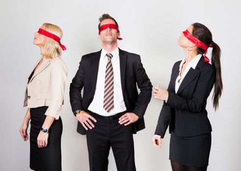 Group of disoriented businesspeople with red ribbons on eyes