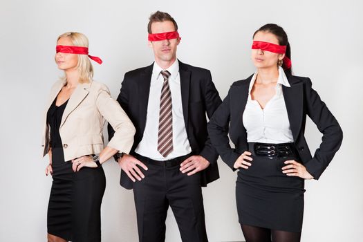 Group of disoriented businesspeople with red ribbons on eyes