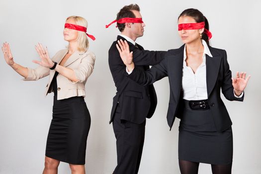 Group of disoriented businesspeople with red ribbons on eyes