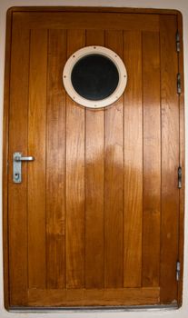 a cruise ships wooden entry door with port hole