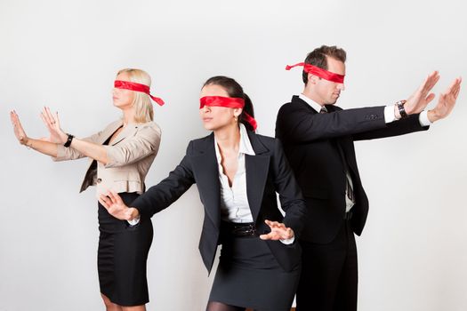 Group of disoriented businesspeople with red ribbons on eyes