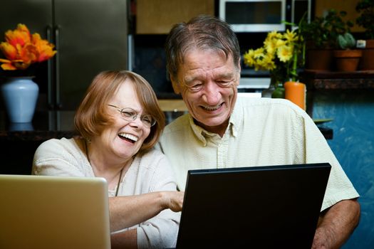 Senior couple using two laptop computers at home