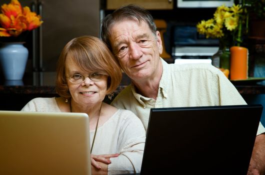 Senior couple using two laptop computers at home