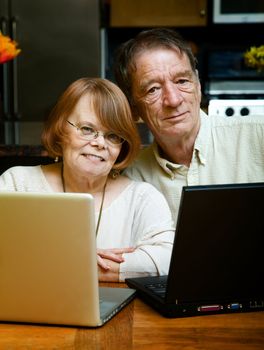 Senior couple using two laptop computers at home