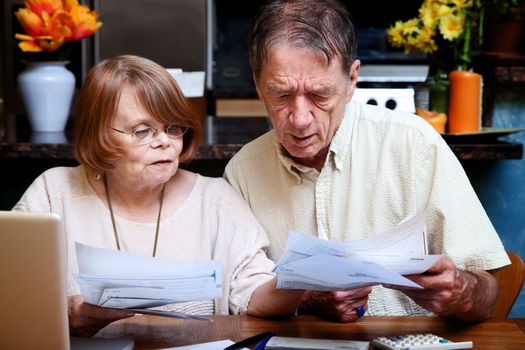 Senior couple at home organizing many bills