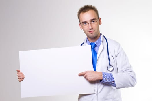 young caucasian doctor holding blank board and pointing