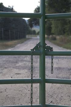 A road stretches out past a locked metal gate.