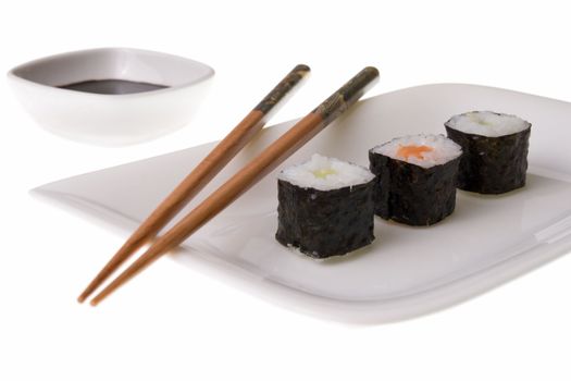 Three makizushi sushirolls and chopsticks on a plate. Soy sauce. Isolated on white