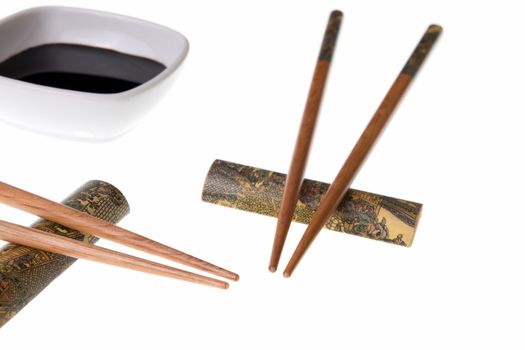 Two pairs of wooden chopsticks and soy sauce. Sticks are decorated with temple theme ornamentation. Isolated on white