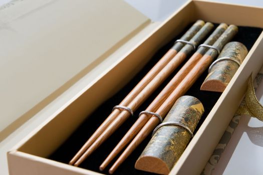 Two pairs of wooden chopsticks in the opened case. Sticks are decorated with temple theme ornamentation