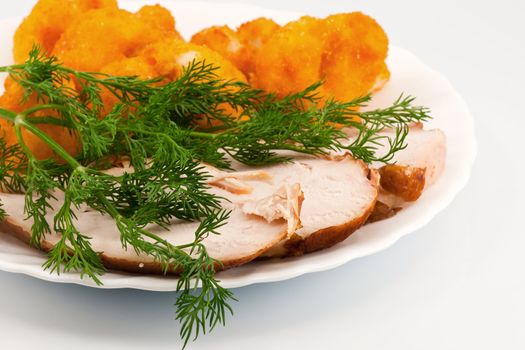 Rosted cauliflower with hot smoked chiken meat and fresh dill on white porcelain plate