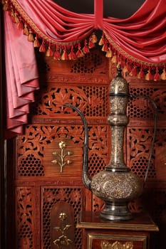 Beautiful copper an amphora against a wooden carved screen
