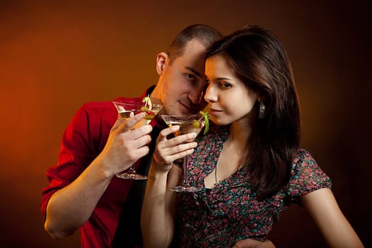 Young couple drinking martini together. Studio shot