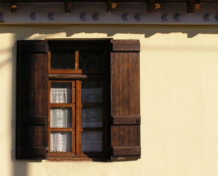 Window with lacy curtains and wooden shades.