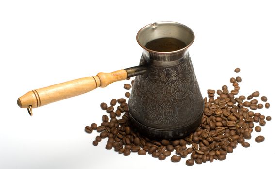 Copper coffee maker with the wooden handle and coffee grains on a white background.