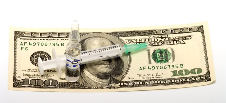 Syringe and ampoule with medicine on  a banknote one hundred dollars.