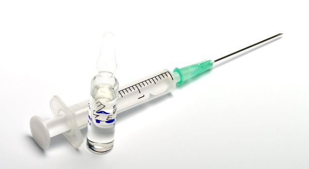 Syringe and ampoule with a vaccine on a white background.