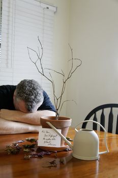 A man with his head down after realizing that he did not water a plant.