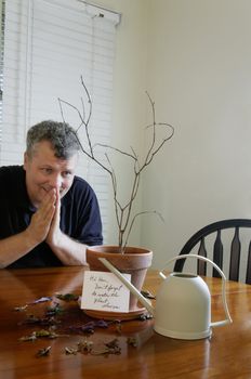 A man praying after realizing that he forgot to water his wife's plant.