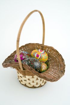 five painted eggs in basket on whie background