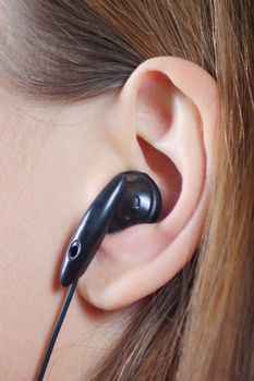 Ear of the young girl with an ear-phone removed close up