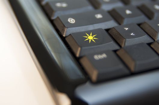 Closeup of keys of a black computer keyboard: over one key, a yellow sun