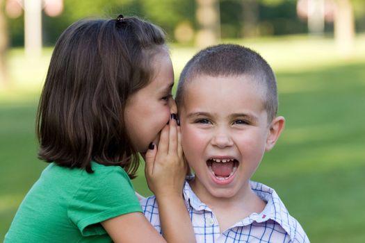 A young girl telling her brother a secret.