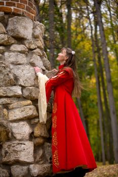 lady in medieval red dress standing near old wall
