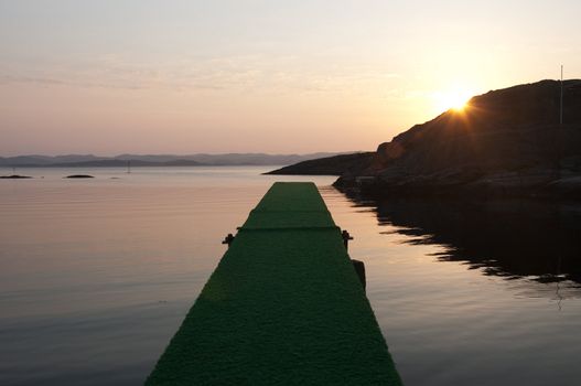 Looking out from a divingboard at the ocean in the sunset