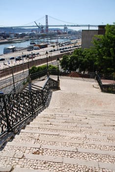 beautiful view to famous lisbon bridge with vintage staircase and lamp posts