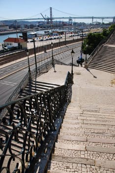 beautiful view to famous lisbon bridge with vintage staircase and lamp posts