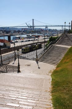 beautiful view to famous lisbon bridge with vintage staircase and lamp posts