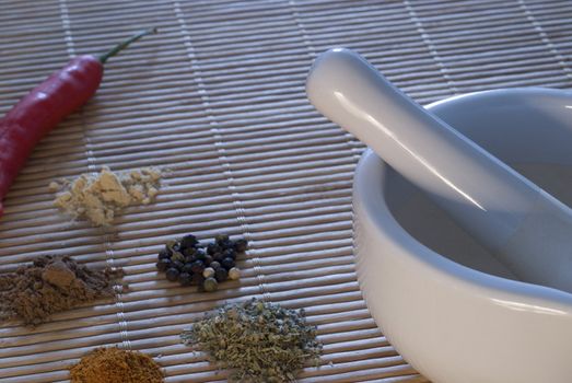 a white pestle and mortar with a selection of spices