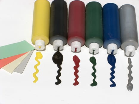Six bottles of colorful paint are spilling on a white surface, and a few card samples are on the side.