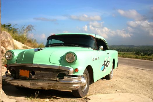 Old car near road over blue sky with clouds