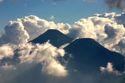Two volcano in clouds and blue sky