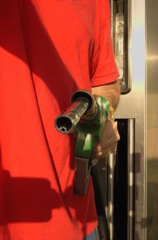 Close-up of a motorist's hand, holding a petrol nozzle.