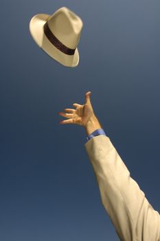A hat, being thrown into the clear blue sky. Motion blur on the hat brim and hand. Focus on the centre of the hat.
