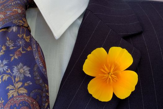 Close-up of a bright buttonhole flower on a businessman's pinstripe suit, contrasting with the flower on his tie.