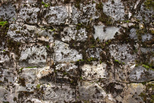 Wall from old stones with green grass